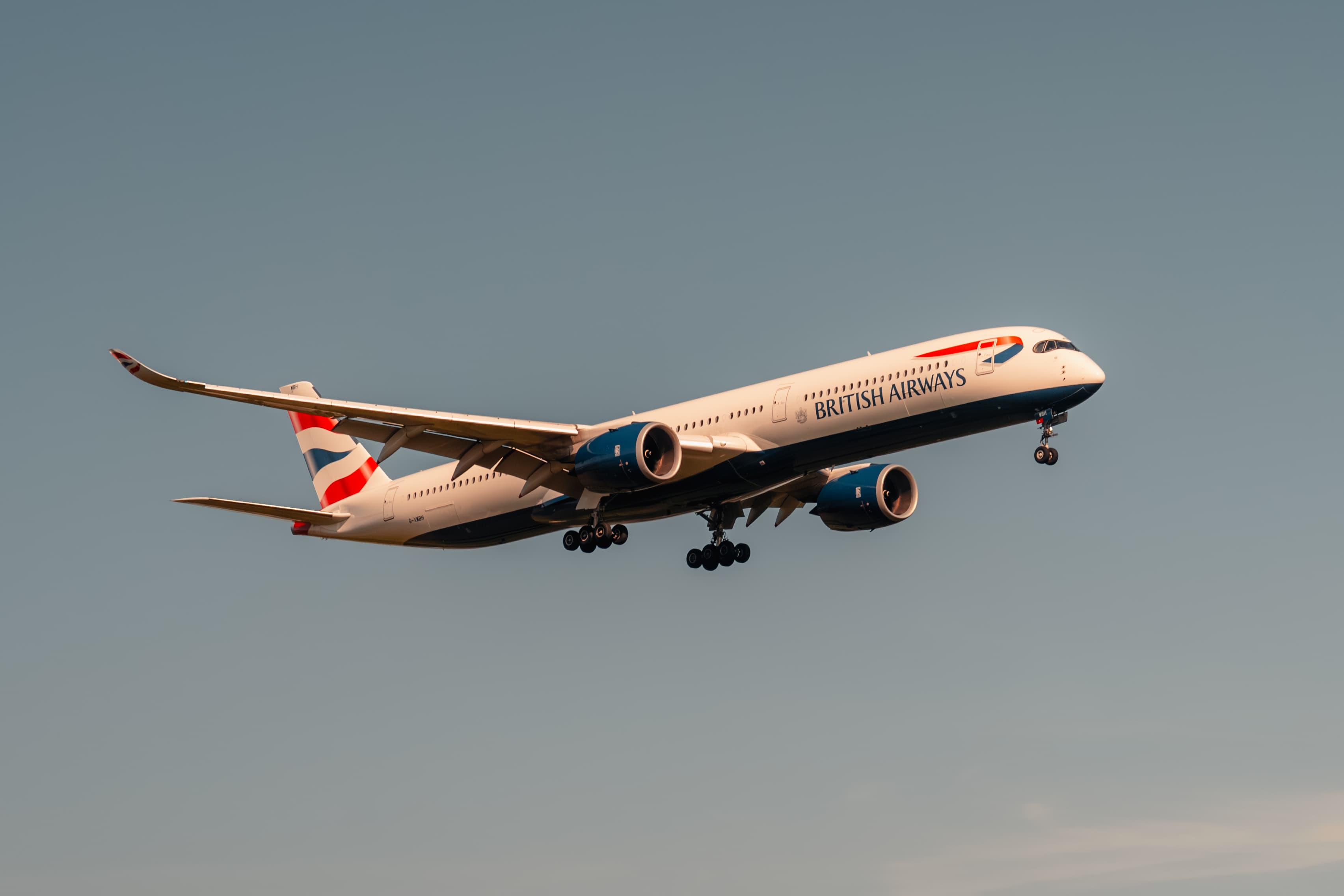 Airbus A350 British Airways en vol, train d’atterrissage sorti, dans une lumière dorée.