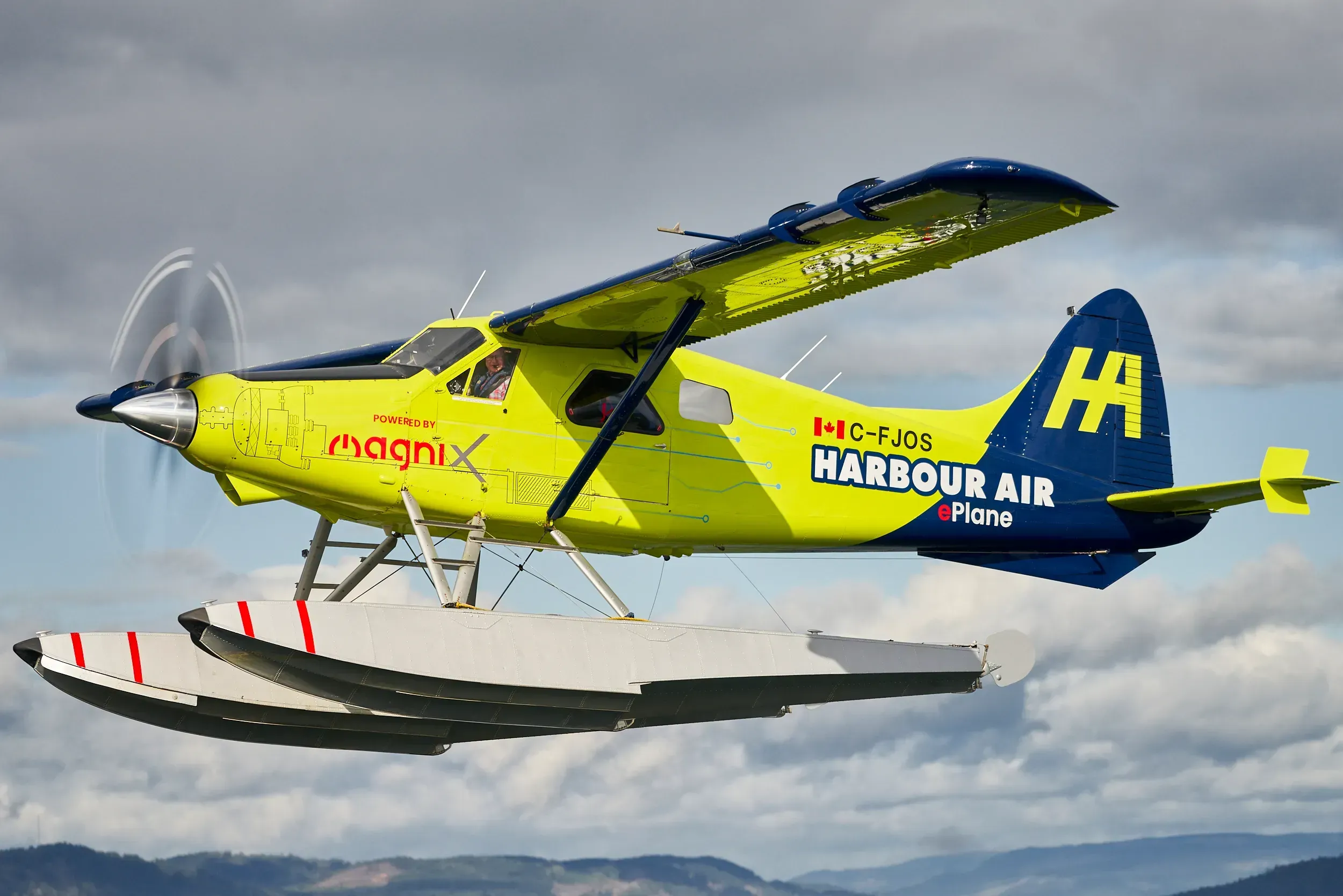 Hydravion électrique ePlane de Harbour Air, jaune et bleu, en vol au-dessus des nuages