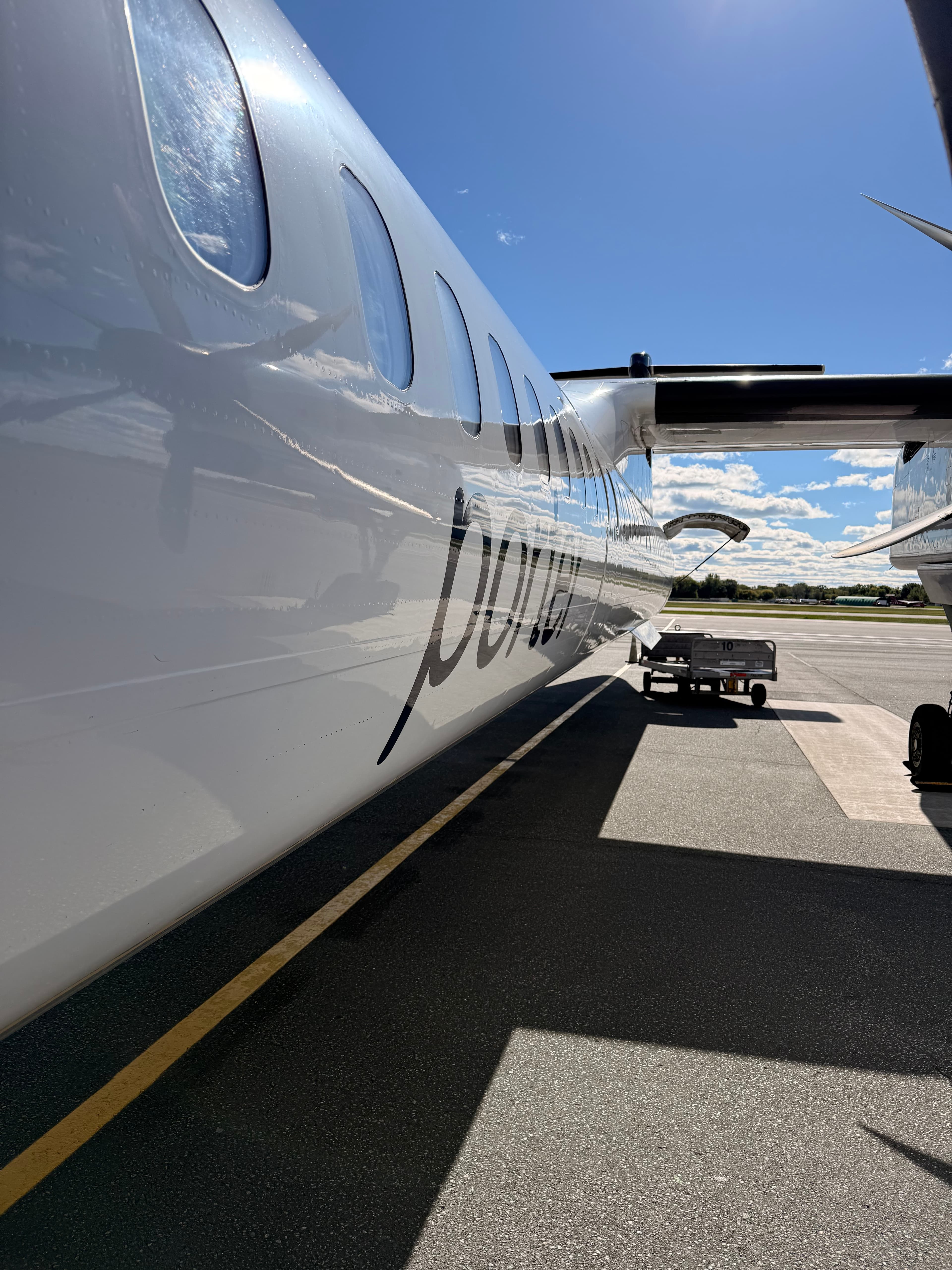 Fuselage d’un Dash 8 Porter sur le tarmac à Toronto, avec le logo de la compagnie et l’aile visibles.
