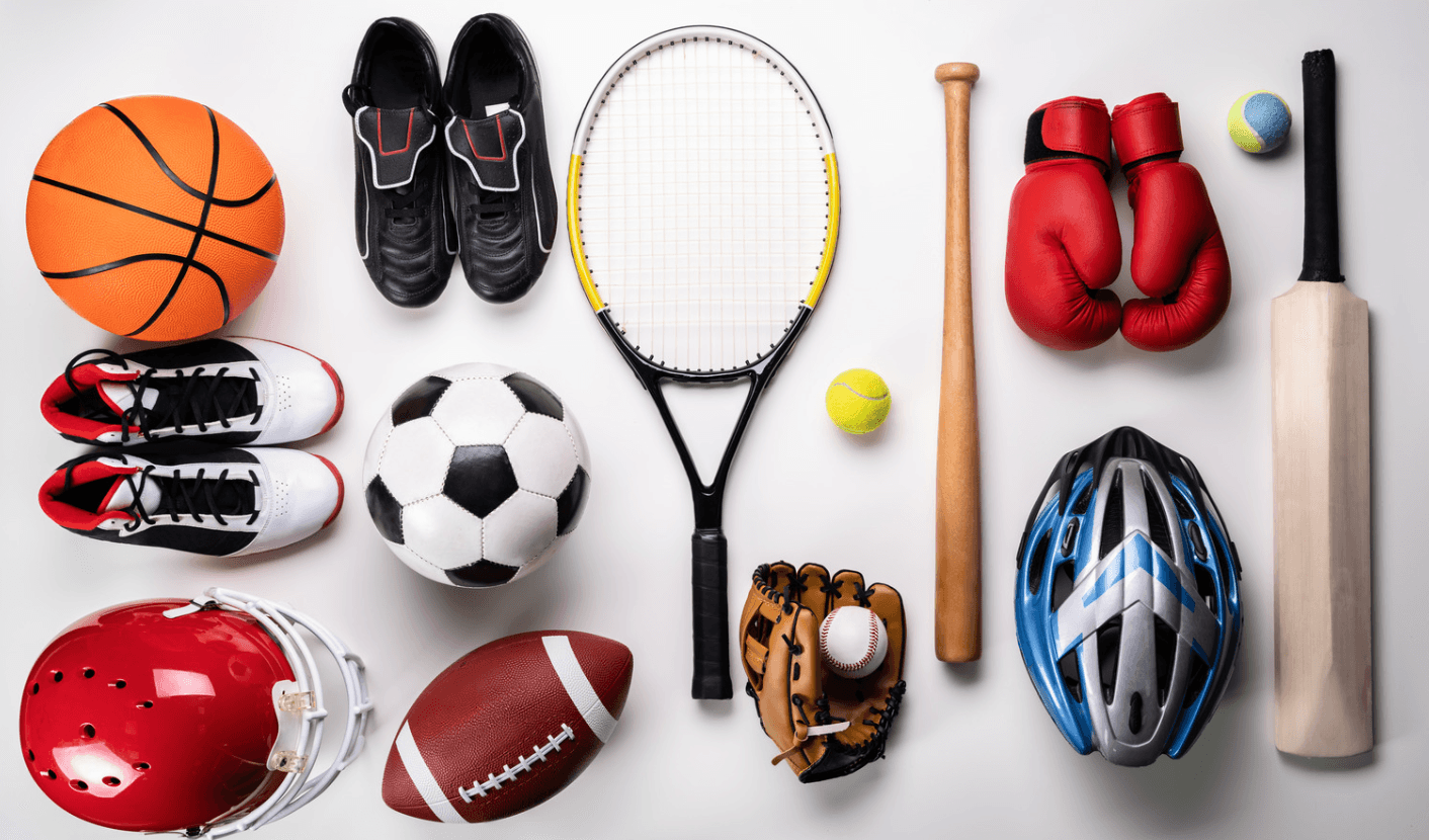 Assortiment d'équipement sportif posé au sol : ballons, raquette, gants de boxe, casques et bâtons