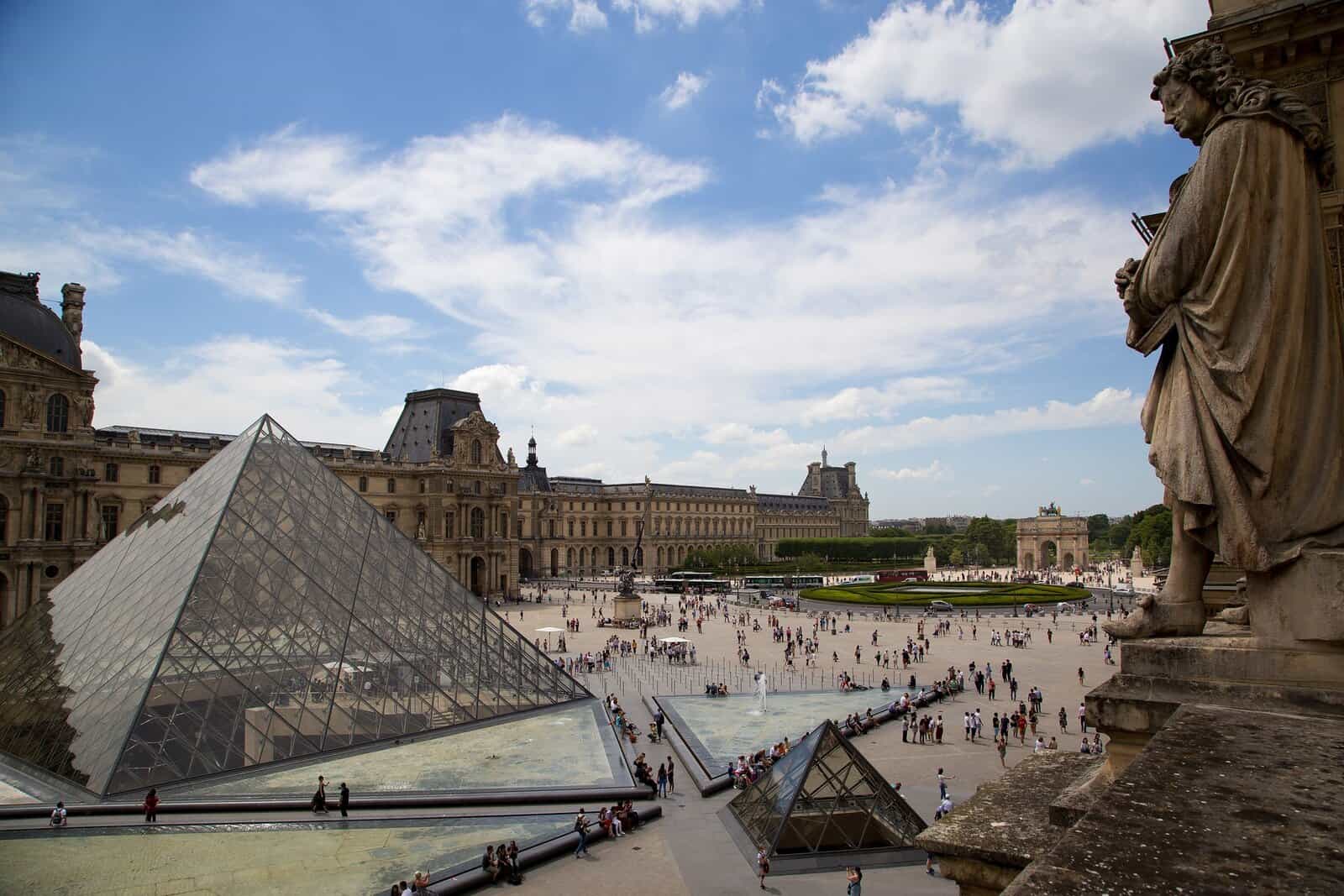 Cour Napoléon at the Louvre in Paris, with the glass pyramid and the Arc de Triomphe du Carrousel in the background