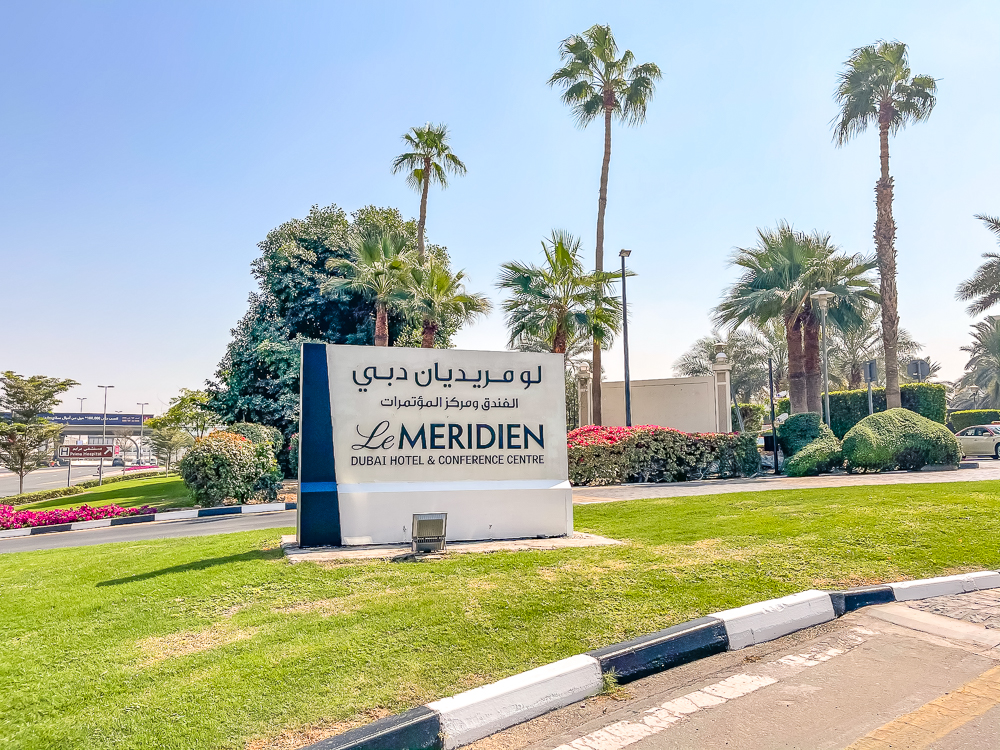 Enseigne extérieure principale du le meridien dubai hotel conference entourée de palmiers et jardins paysagers
