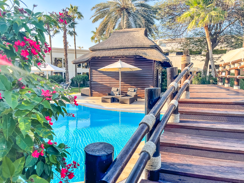 Terrasse en bois avec piscine et cabane tiki au le meridien dubai hotel conference sous les palmiers