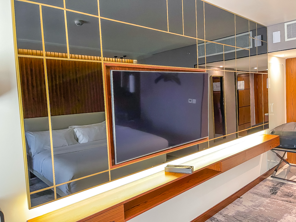 Télévision murale avec miroirs dorés et meuble TV en bois au le meridien dubai hotel conference