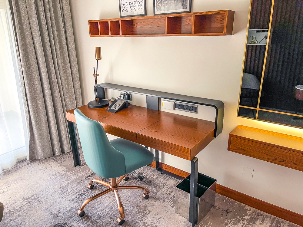 Bureau de travail moderne avec chaise verte et rangements dans une chambre du le meridien dubai hotel conference