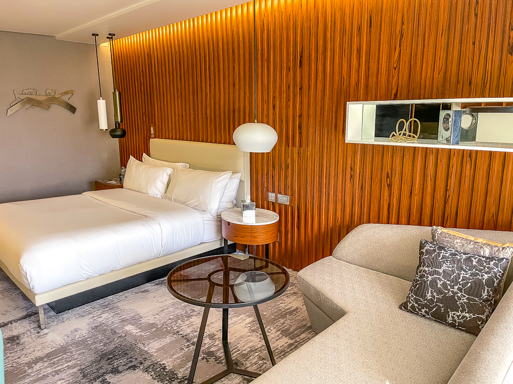 Lit king size confortable avec tête de lit en bois et éclairage moderne au le meridien dubai hotel conference