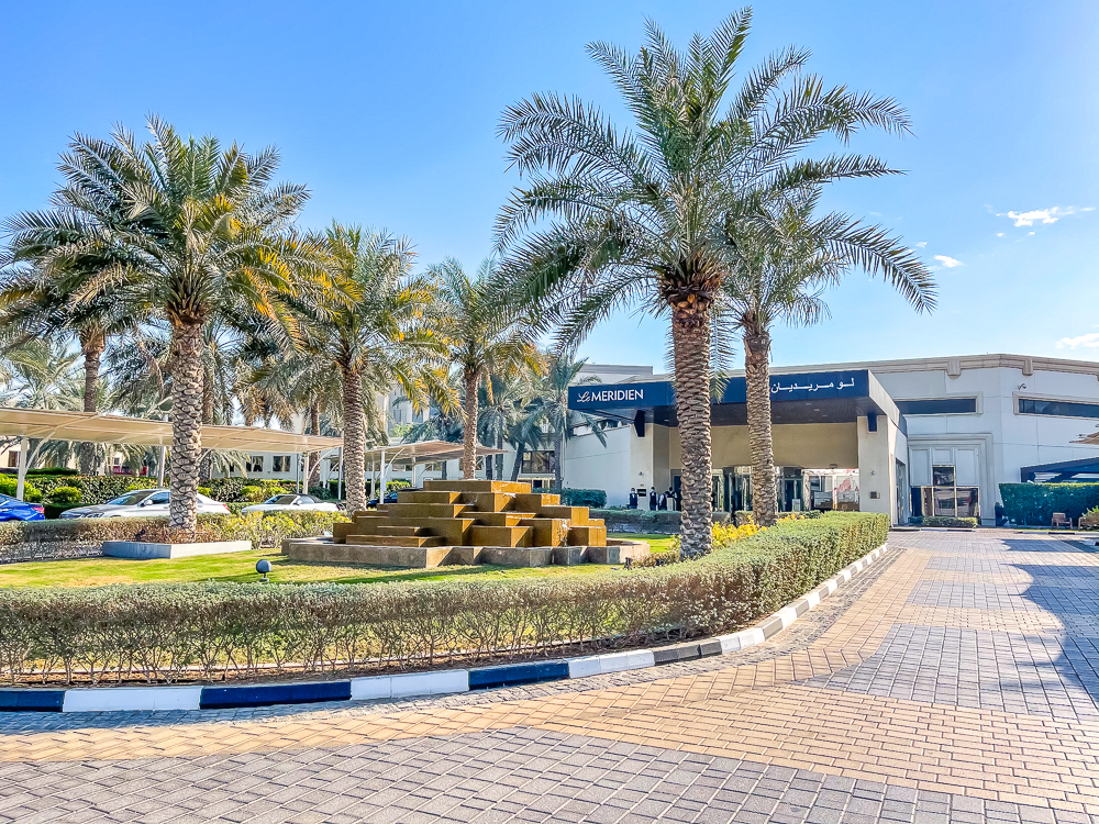Facade principale avec palmiers et jardins paysagers du le meridien dubai hotel conference sous un ciel bleu