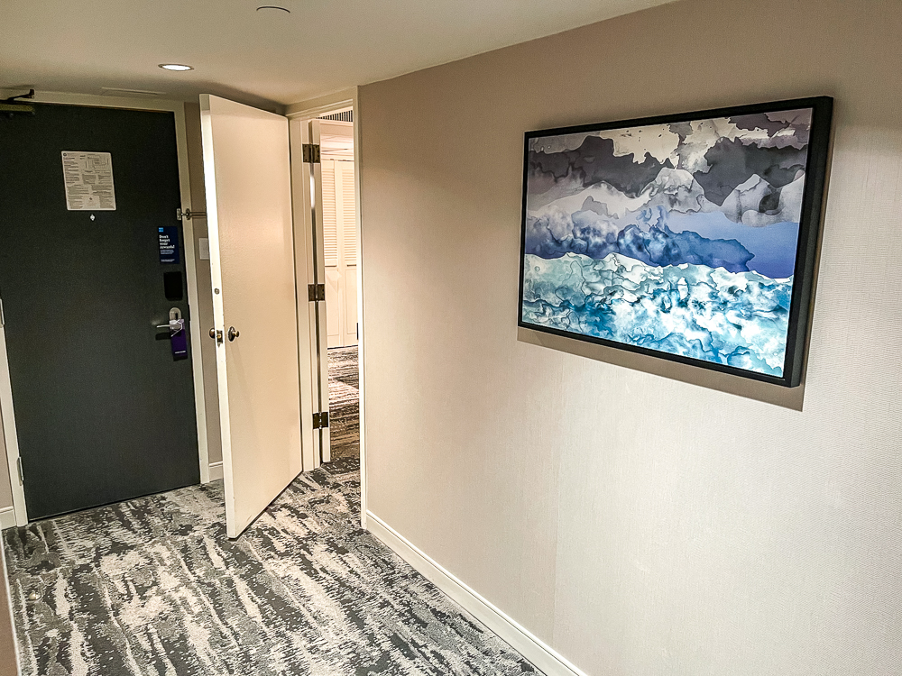 Entrée spacieuse d'une chambre au hyatt regency vancouver avec couloir moderne et œuvre d'art contemporaine