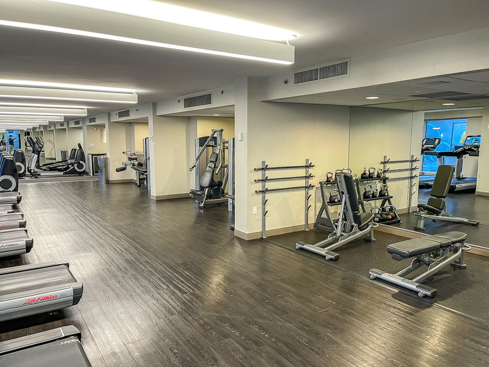 Salle de sport moderne du hyatt regency vancouver avec tapis de course et équipements cardio face aux fenêtres