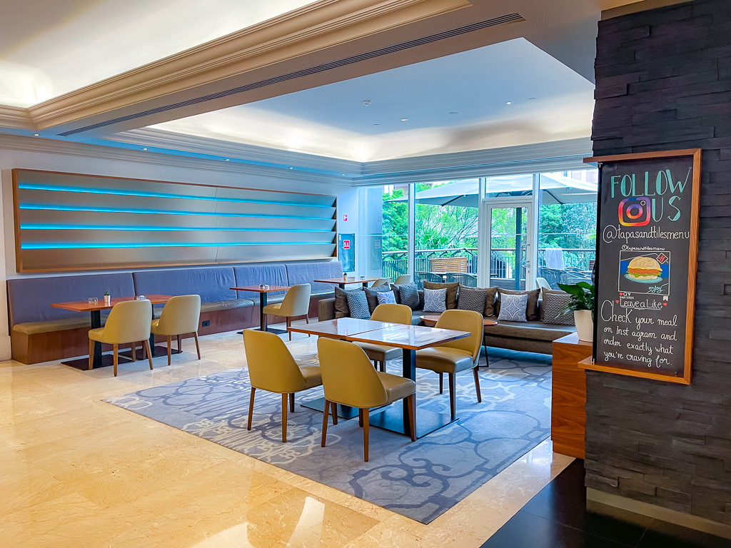 Modern lobby bar at the Marriott Lisbon with wooden counter, high stools, and contemporary lounge atmosphere