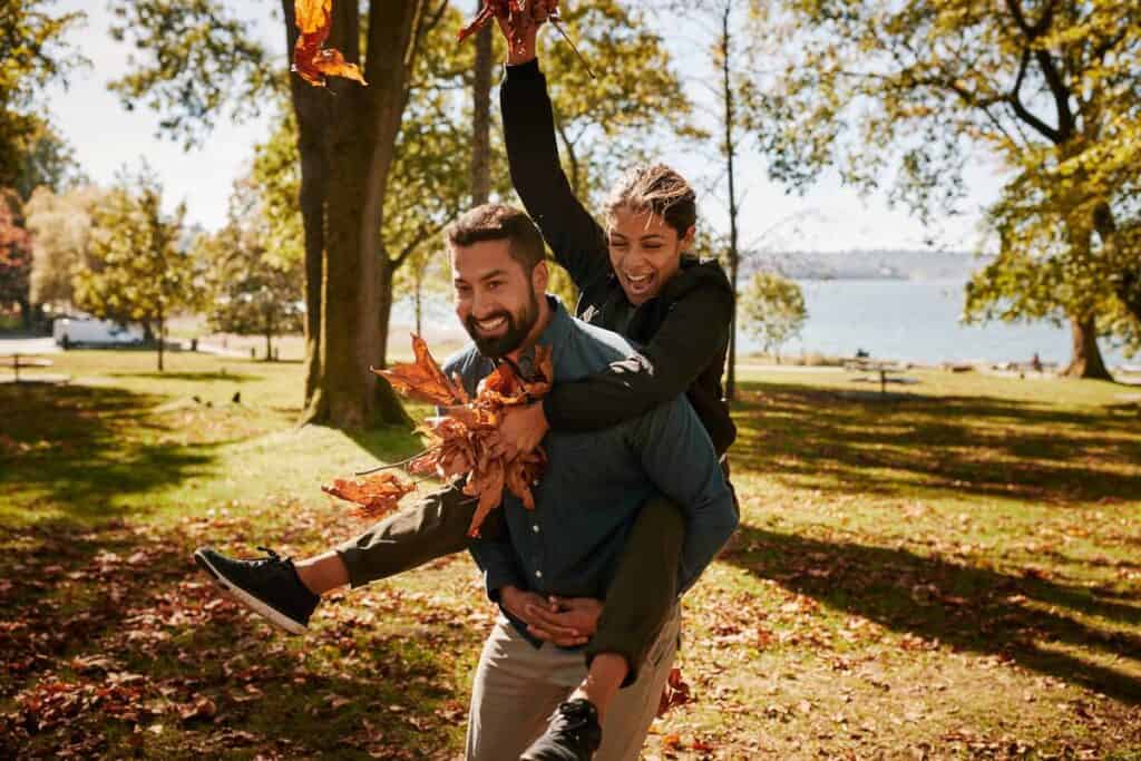 Couple playing in the park with autumn leaves