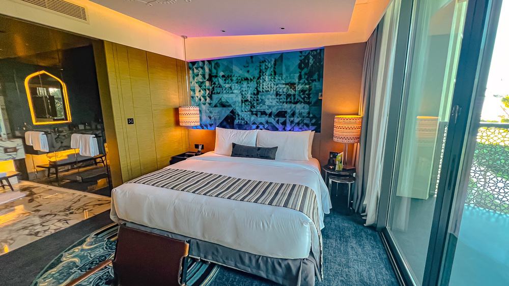 Suite panoramique du w muscat avec salon, chambre et salle de bain ouverte, décoration moderne aux tons bleus et dorés