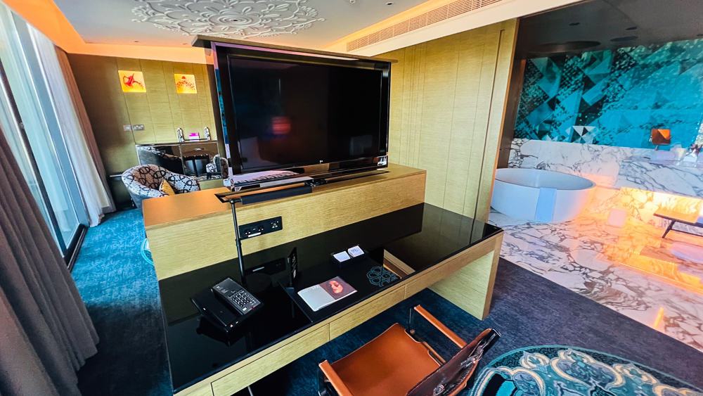 Console TV du w muscat avec rangements intégrés, télévision grand écran et vue sur la salle de bain en arrière-plan