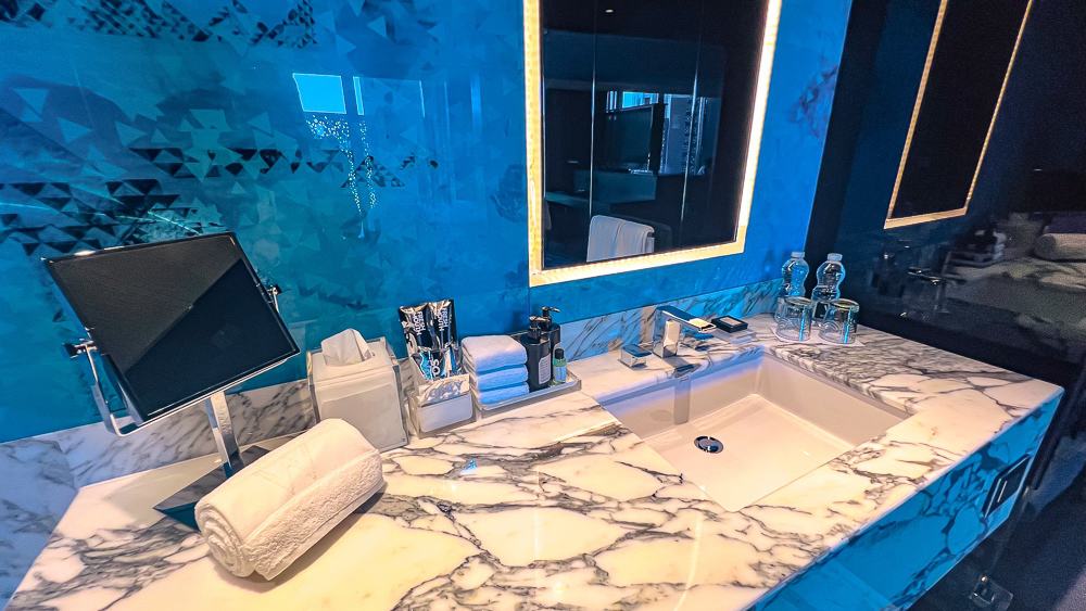 Vasque design du w muscat en marbre veiné avec miroir LED, carrelage bleu géométrique et robinetterie moderne luxueuse