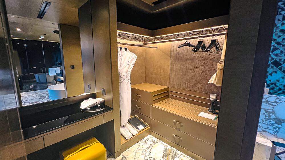 Walk-in closet du w muscat avec penderie design, art mural traditionnel omanais et aménagements luxury en bois naturel