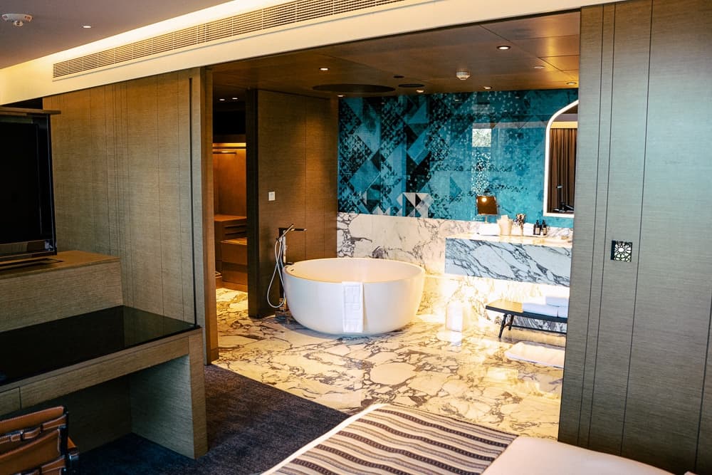 Salle de bain luxueuse du w muscat avec baignoire îlot blanche, carrelage bleu géométrique et finitions en marbre veiné