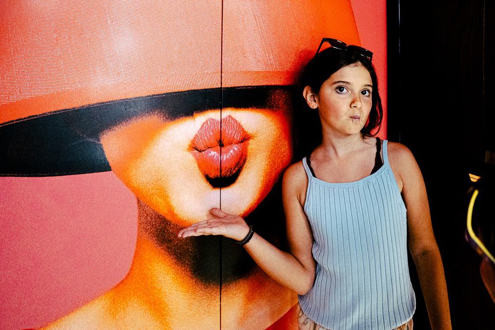 Art mural coloré avec motifs de lèvres oranges dans le lobby moderne du w muscat, femme posant devant l'œuvre artistique