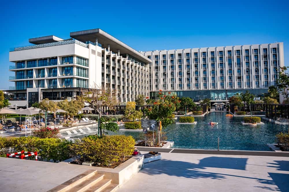Façade moderne du w muscat avec architecture contemporaine blanche, piscine centrale et jardins paysagers sous ciel bleu