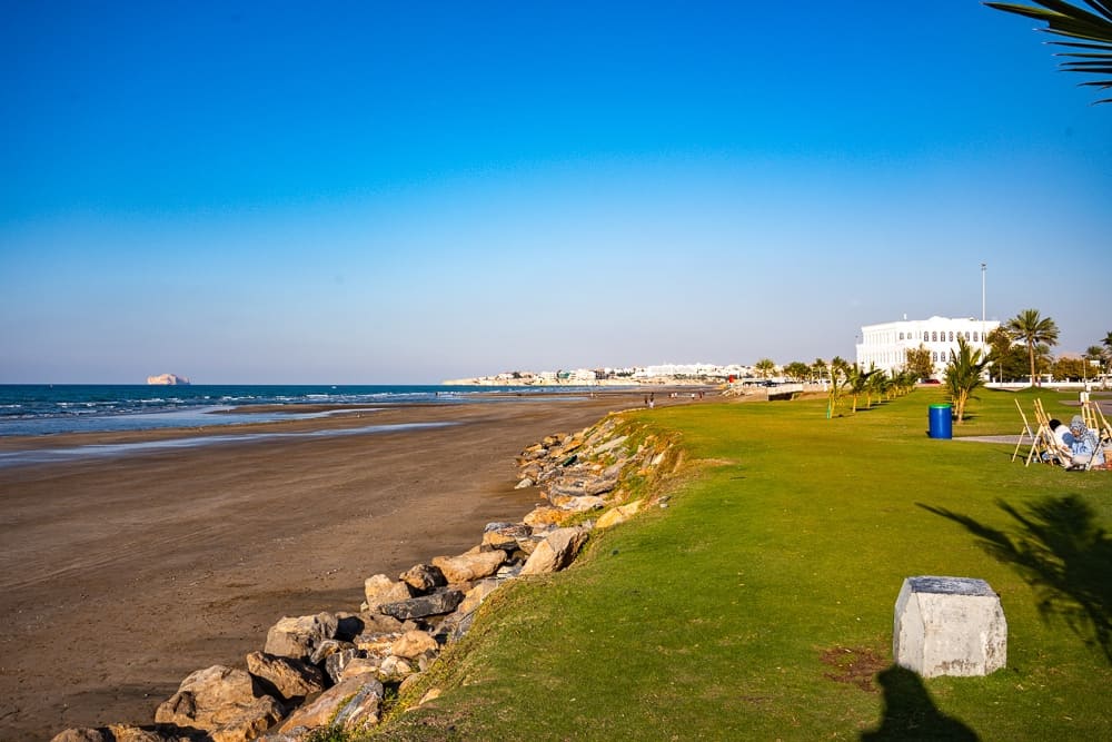 Front de mer paysager du w muscat avec jardins entretenus, palmiers, enrochement et vue panoramique sur la côte omanaise