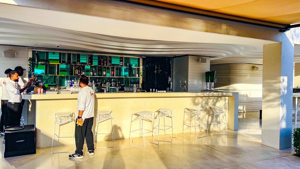 Bar contemporain du w muscat avec comptoir élégant, tabourets en métal et arrière-plan coloré aux tons verts et bleus