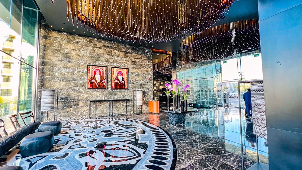 Lobby principal du w muscat avec reception en marbre, plafond design lumineux et sol geometrique impressionnant