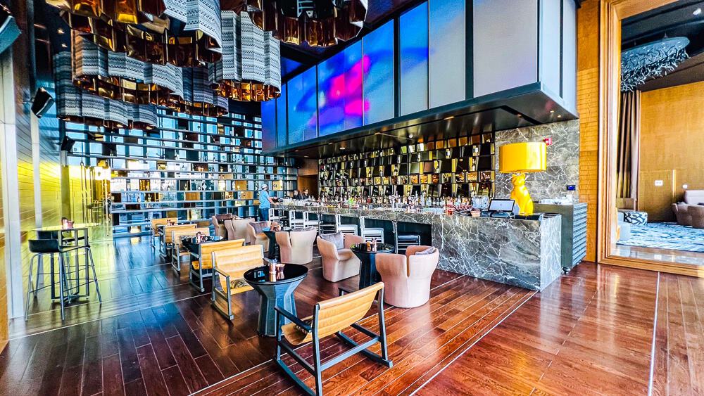 Bar lounge du w muscat avec banquettes courbes, tables basses et vue mer dans une ambiance luxueuse et contemporaine