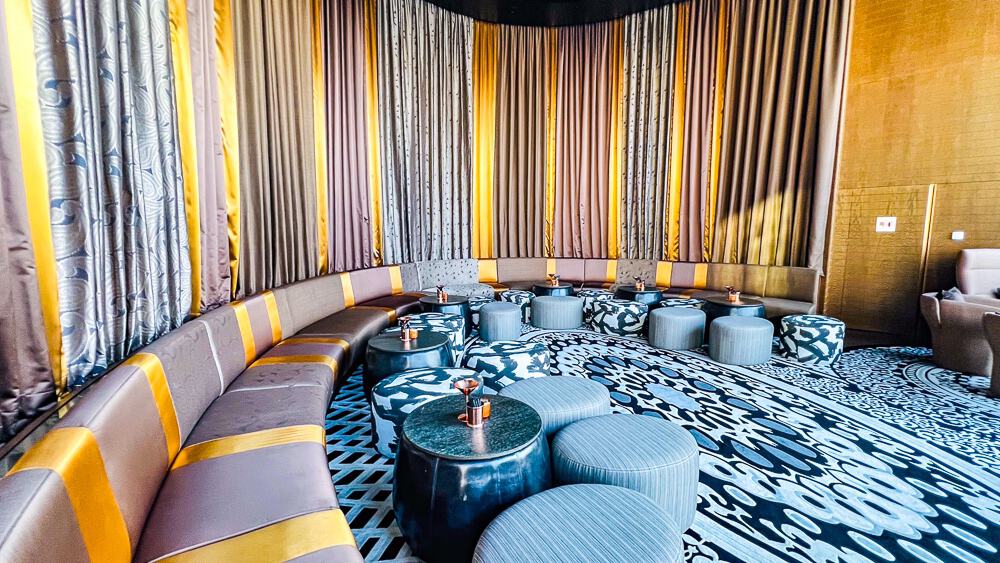 Salon prive du w muscat avec banquette circulaire beige, tapis geometriques et eclairage d'ambiance contemporain