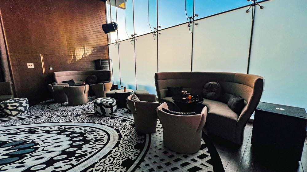 Salon lounge du w muscat avec fauteuils design, eclairage suspendu et grandes baies vitrees dans ambiance feutree