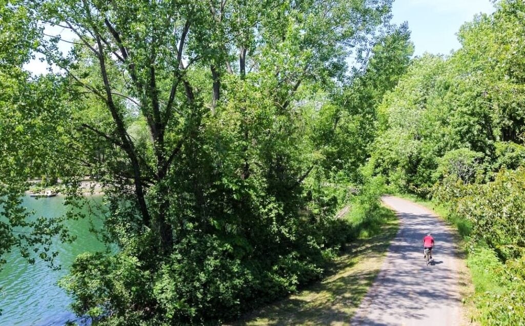 Un cycliste est sur une piste cyclable, au coeur de la nature