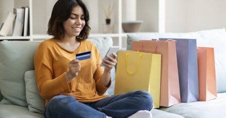 Femme avec ses achats assis sur un sofa et une carte en main