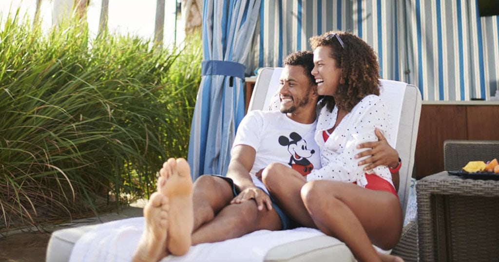 Un couple souriant se détend sur une chaise longue près de la nature. Chandail Mickey Mouse