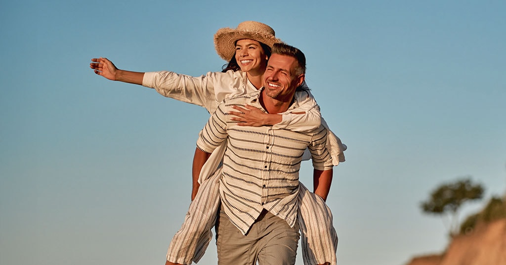 Couple souriant profitant d'une promenade ensoleillée en plein air.