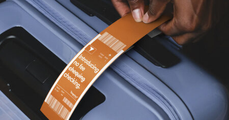 Orange luggage tag on a blue suitcase, with the text "Introducing no fee chequing. No fee checking"