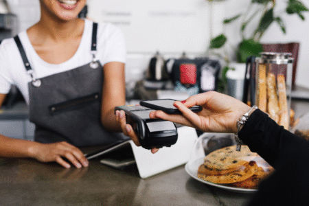 loyalty program newcomers – person paying with phone at coffee shop