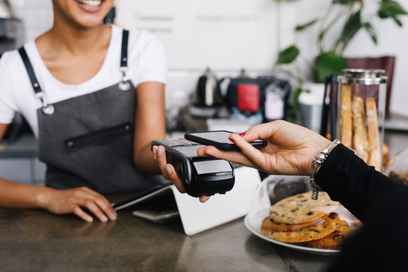 loyalty program newcomers – person paying with phone at coffee shop