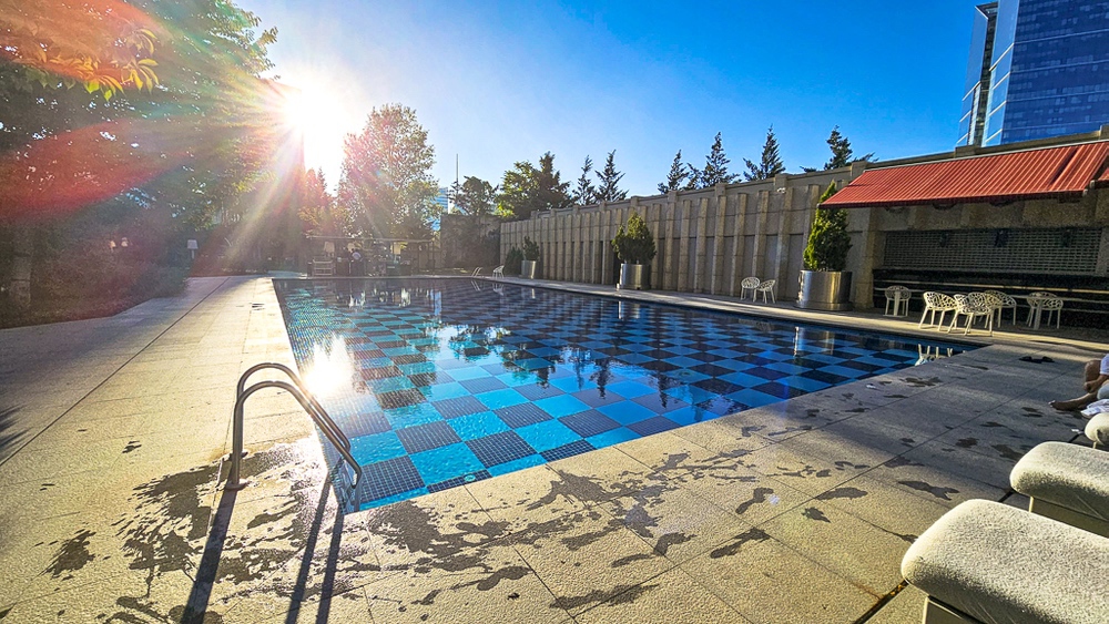 Piscine extérieure sur terrasse du JW Marriott Hotel Ankara avec soleil couchant et transats, vue urbaine