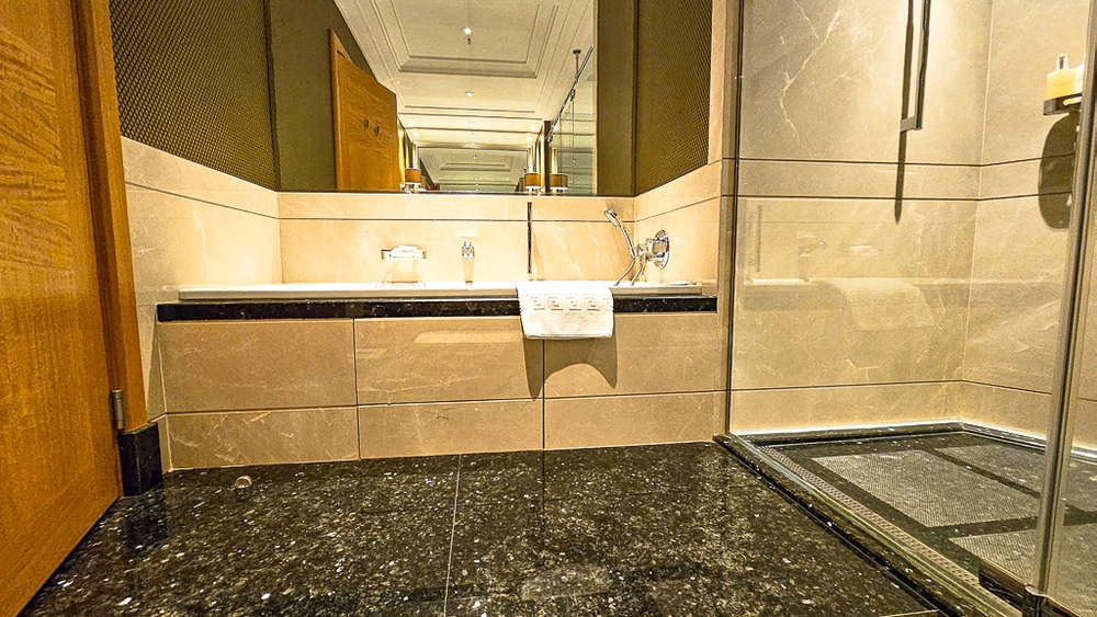 Salle de bain luxueuse en marbre noir et beige au JW Marriott Hotel Ankara avec double vasque et douche vitrée