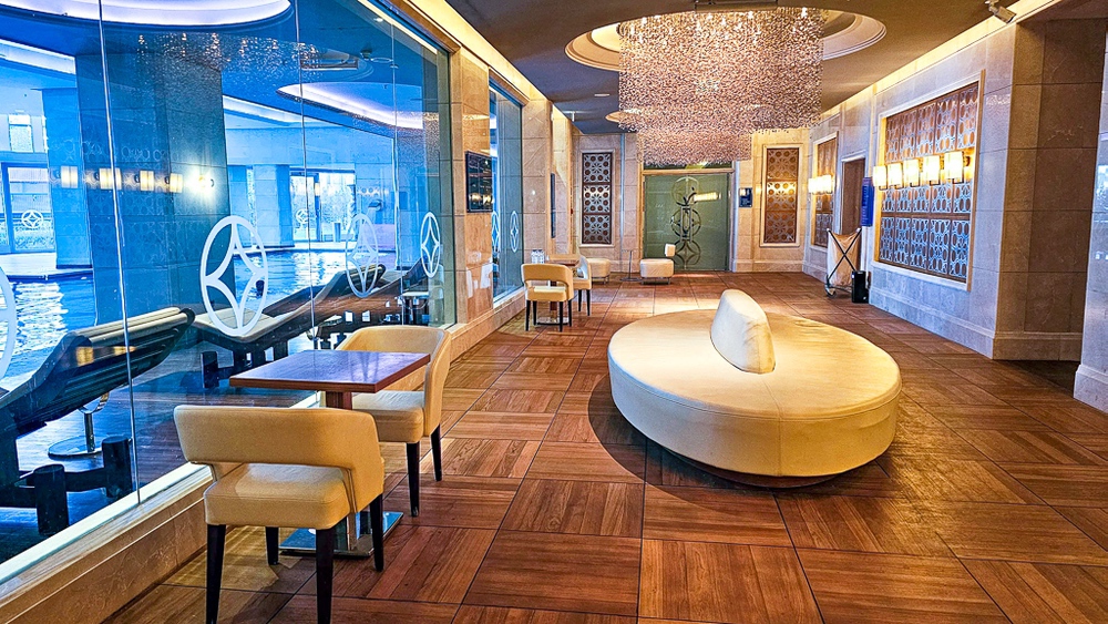 Salon de relaxation du spa du JW Marriott Hotel Ankara avec mobilier blanc et vue sur piscine à travers baies vitrées