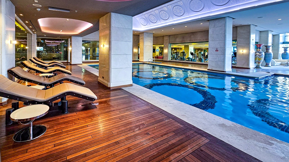 Piscine intérieure luxueuse avec chaises longues en bois au spa du JW Marriott Hotel Ankara, éclairage moderne