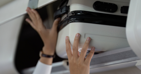 Dimensions des bagages de WestJet – image en vedette – mains plaçant une valise dans le compartiment supérieur