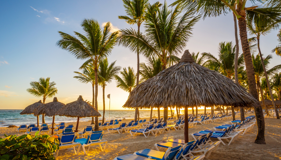 Beach with chairs, umbrellas, and palm trees