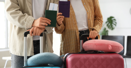Image de deux personnes tenant des passeports et des valises, visibles des épaules aux genoux.