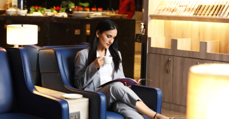 Woman sitting in an armchair in a lounge with a cup of coffee and a magazine