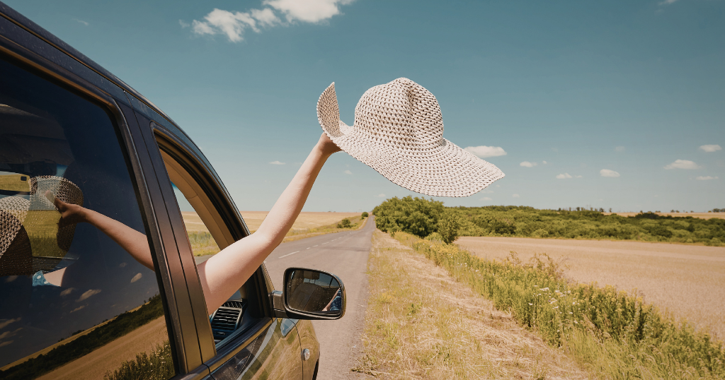 Person with hand and hat out car window