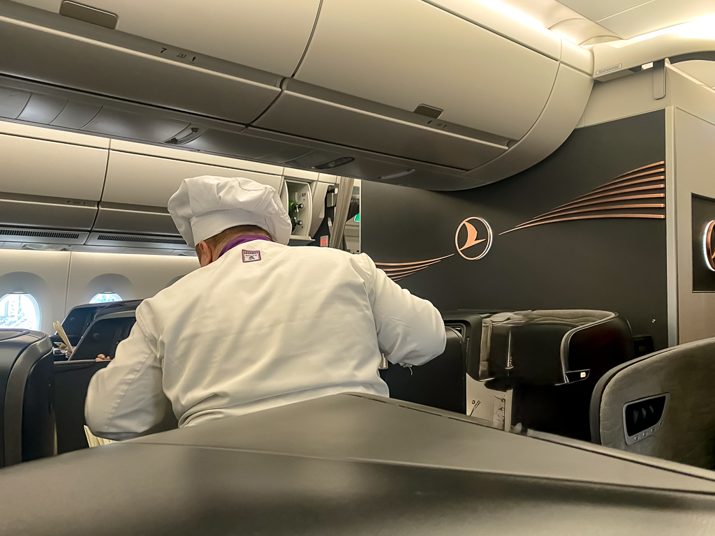 Chef de bord Turkish Airlines en uniforme blanc servant les passagers dans la cabine affaires A350 avec attention personnalisée