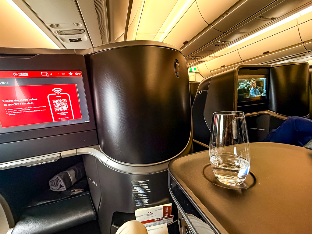 Intérieur spacieux de la cabine affaires Turkish Airlines A350 avec siège et écran personnel, éclairage ambré chaleureux