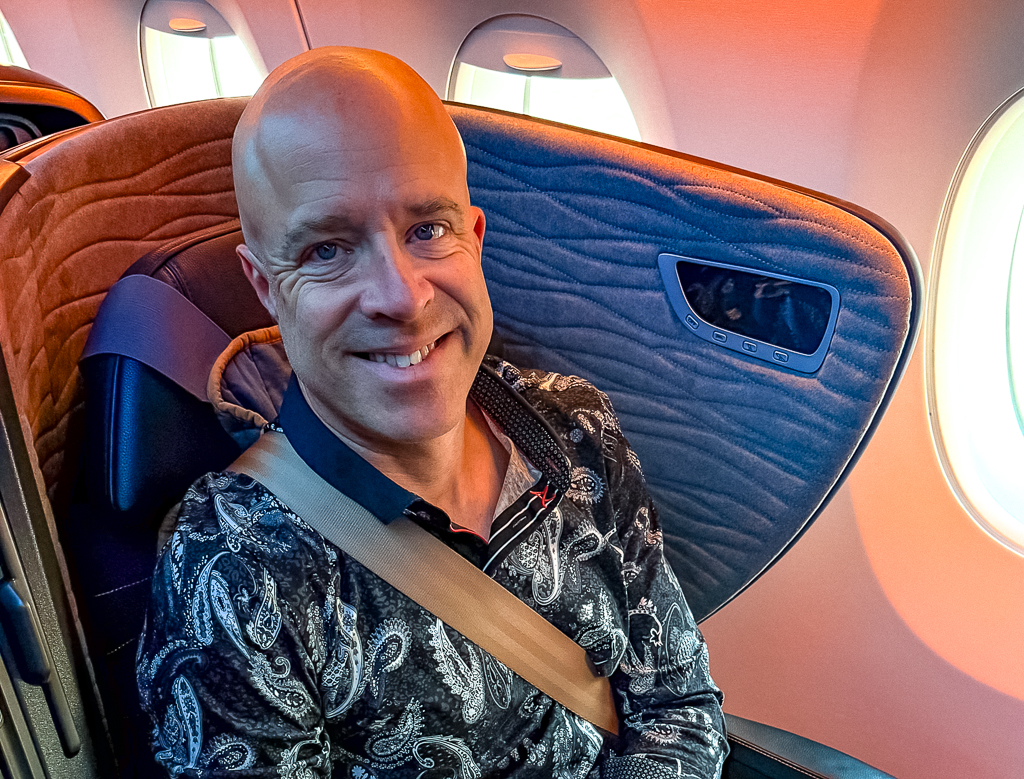 Passager satisfait Turkish Airlines en classe affaires A350, souriant et attaché dans son siège près du hublot