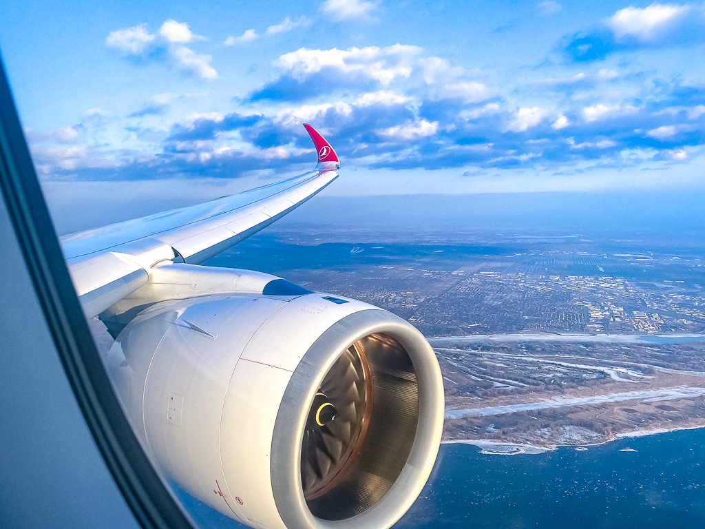 Vue depuis le hublot Turkish Airlines montrant l'aile et le moteur de l'A350 survolant un paysage côtier
