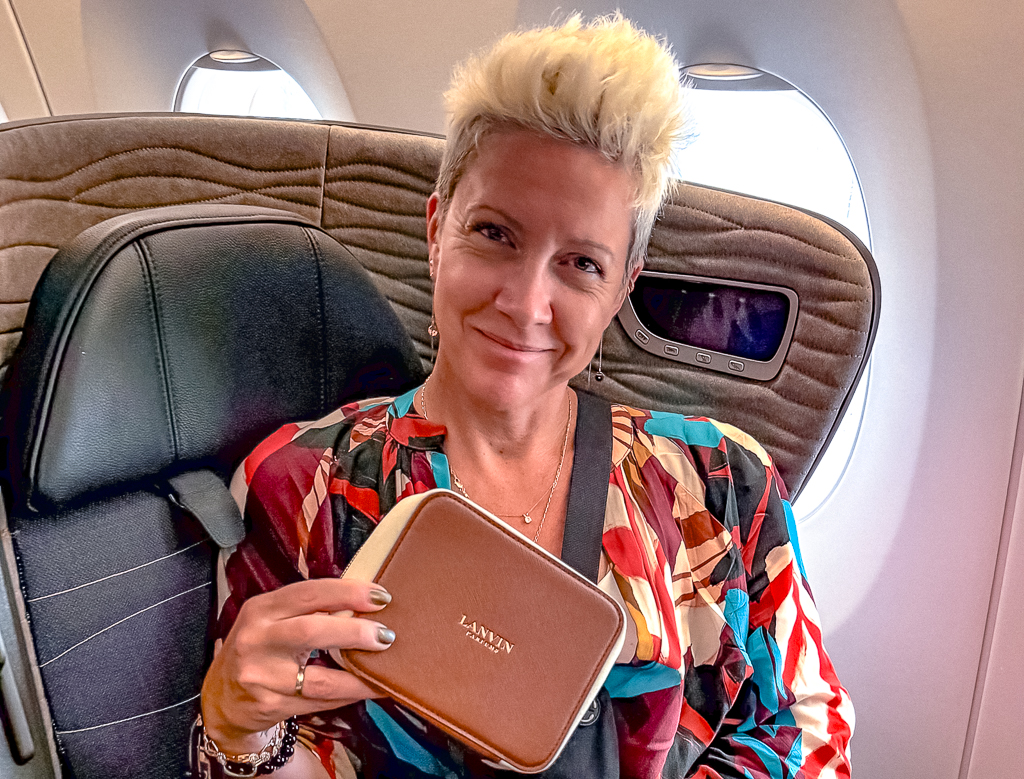 Passagere souriante en classe affaires Turkish Airlines tenant sa trousse amenities dans la cabine luxueuse de l'A350