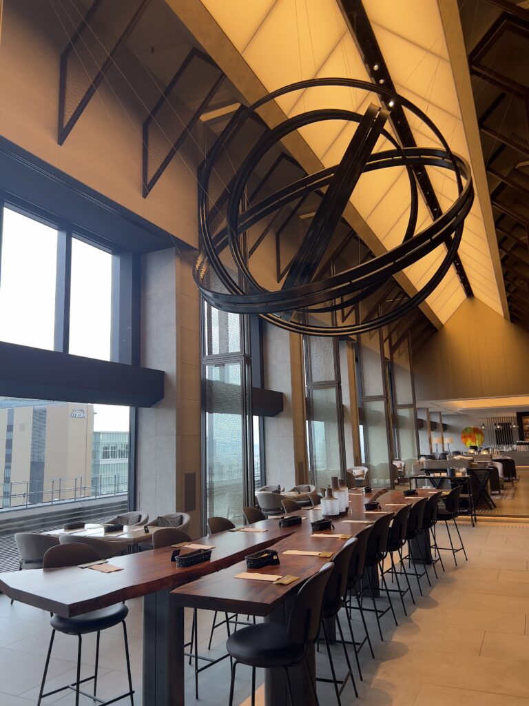 Restaurant principal du Autograph Osaka avec plafond vouté en bois, tables élégantes et suspension circulaire moderne